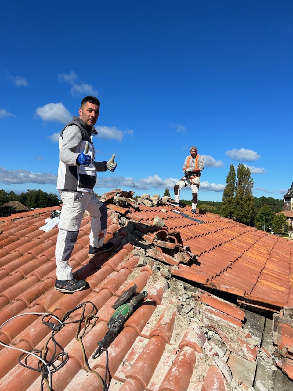 Deux couvreurs de M Picque Couverture sur une toiture en tuiles pendant la dépose du faîtage